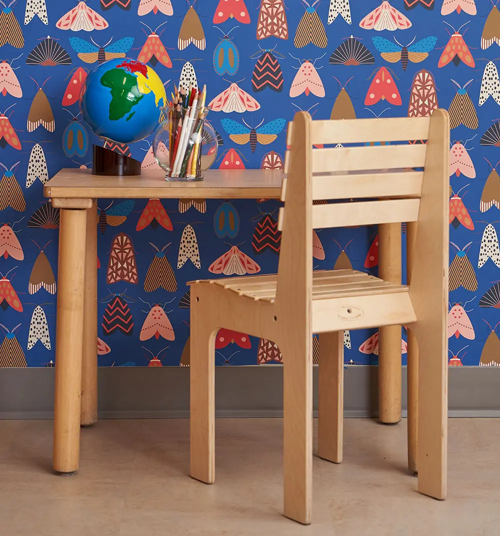 wooden desk and chair with moth wallpaper